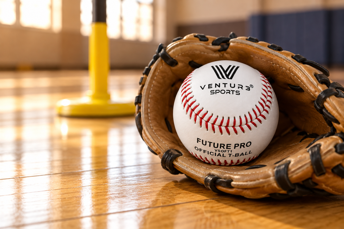 A VSOFT1 T-ball resting in a small youth glove on a gym floor